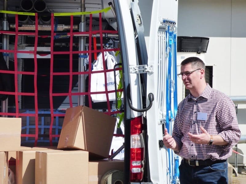 Michael Girbes steht an einem Fahrzeug und zeigt richtige Ladungssicherung {{brizy_dc_image_alt imageSrc=